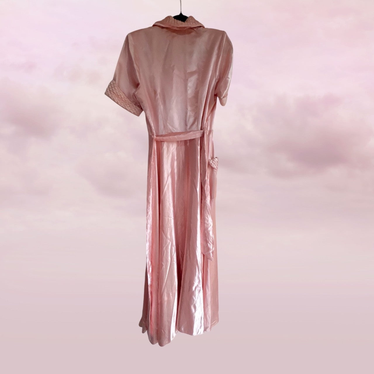 Pink satin robe on a hanger against a pink background