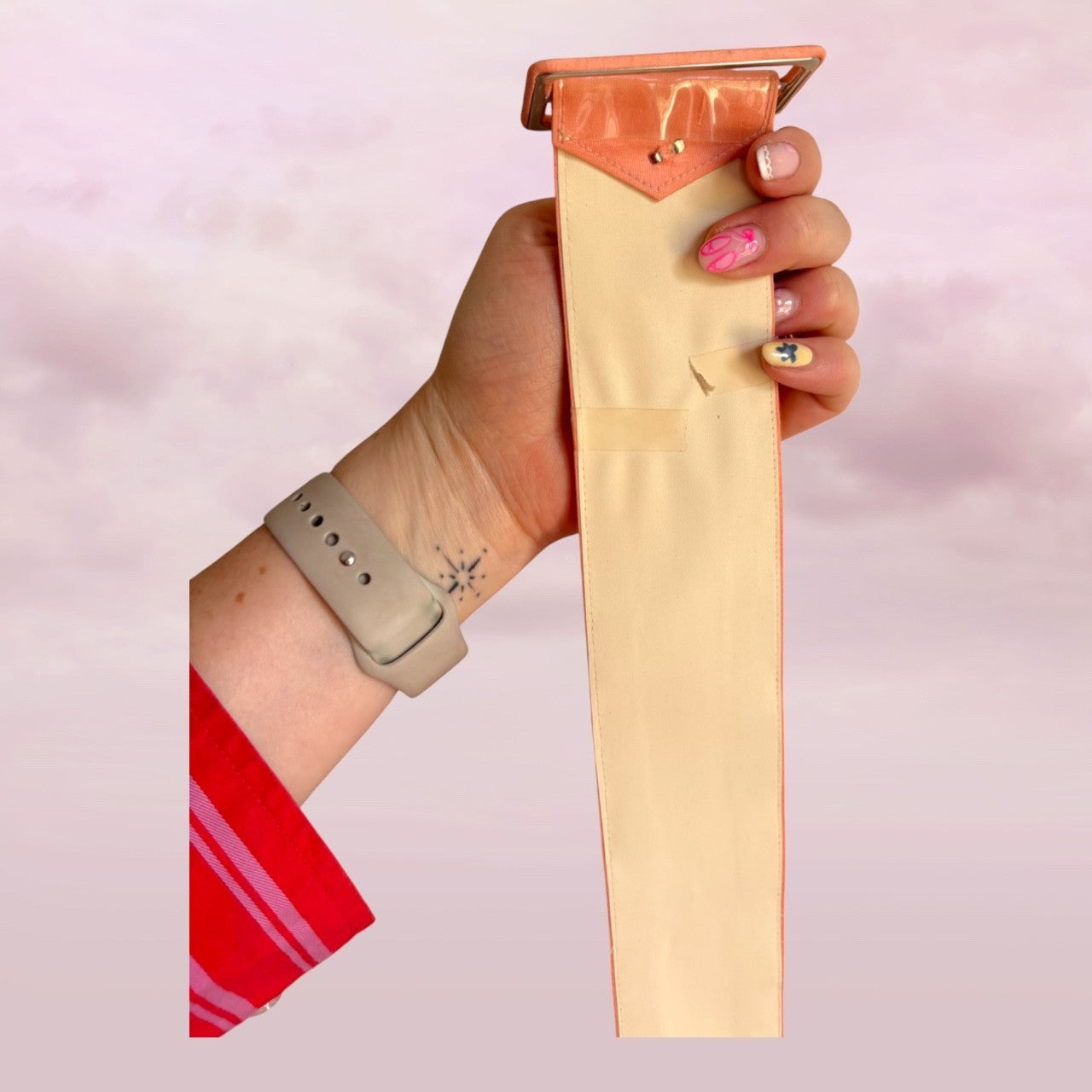 Hand holding a beige hair clipper against a pink background