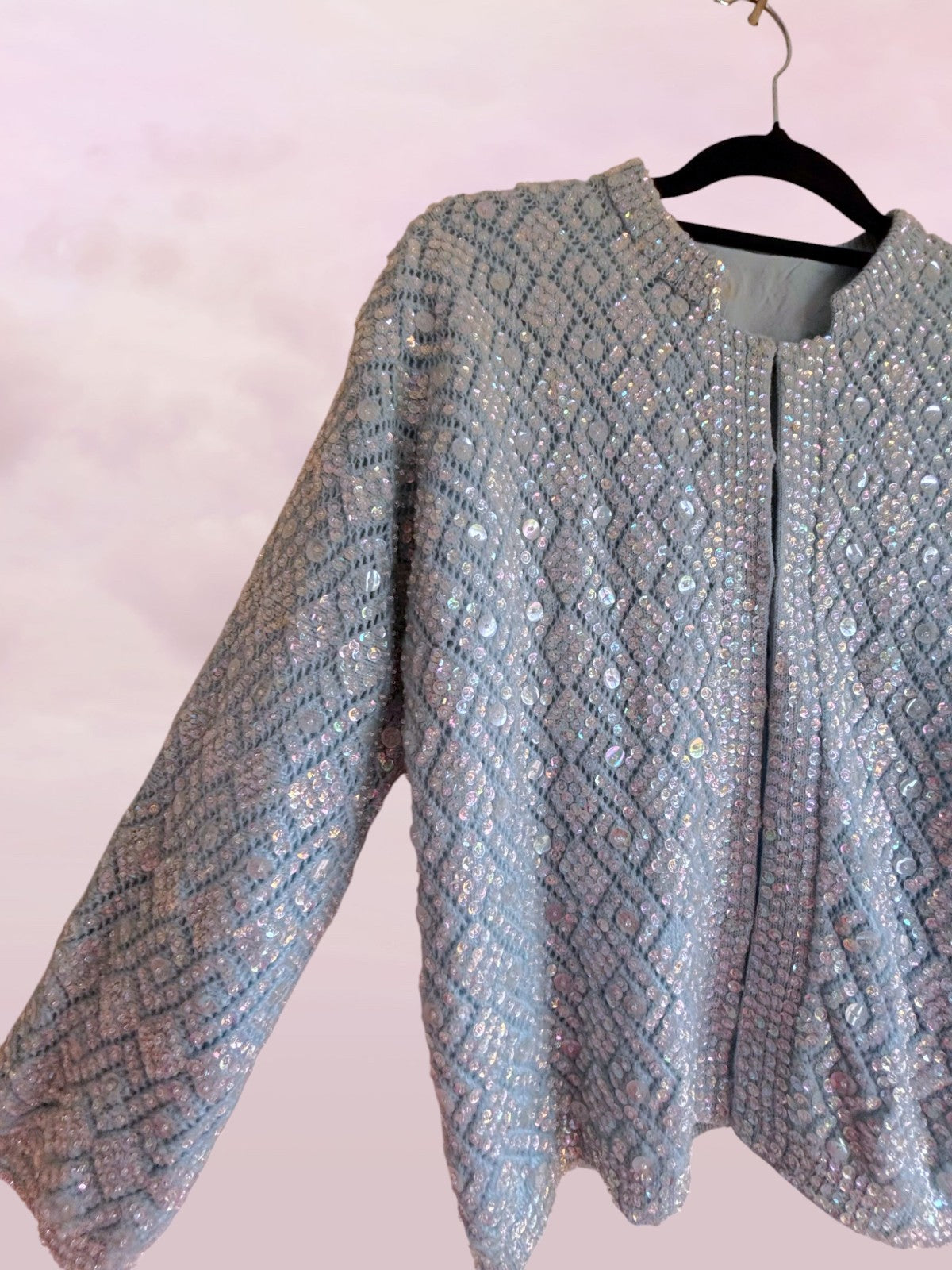 Sequined jacket on a hanger against a pink background