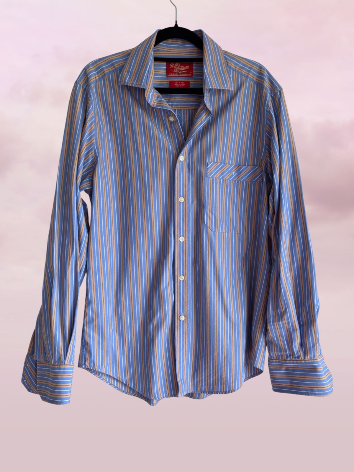 Blue and gray striped shirt on a hanger against a light pink background