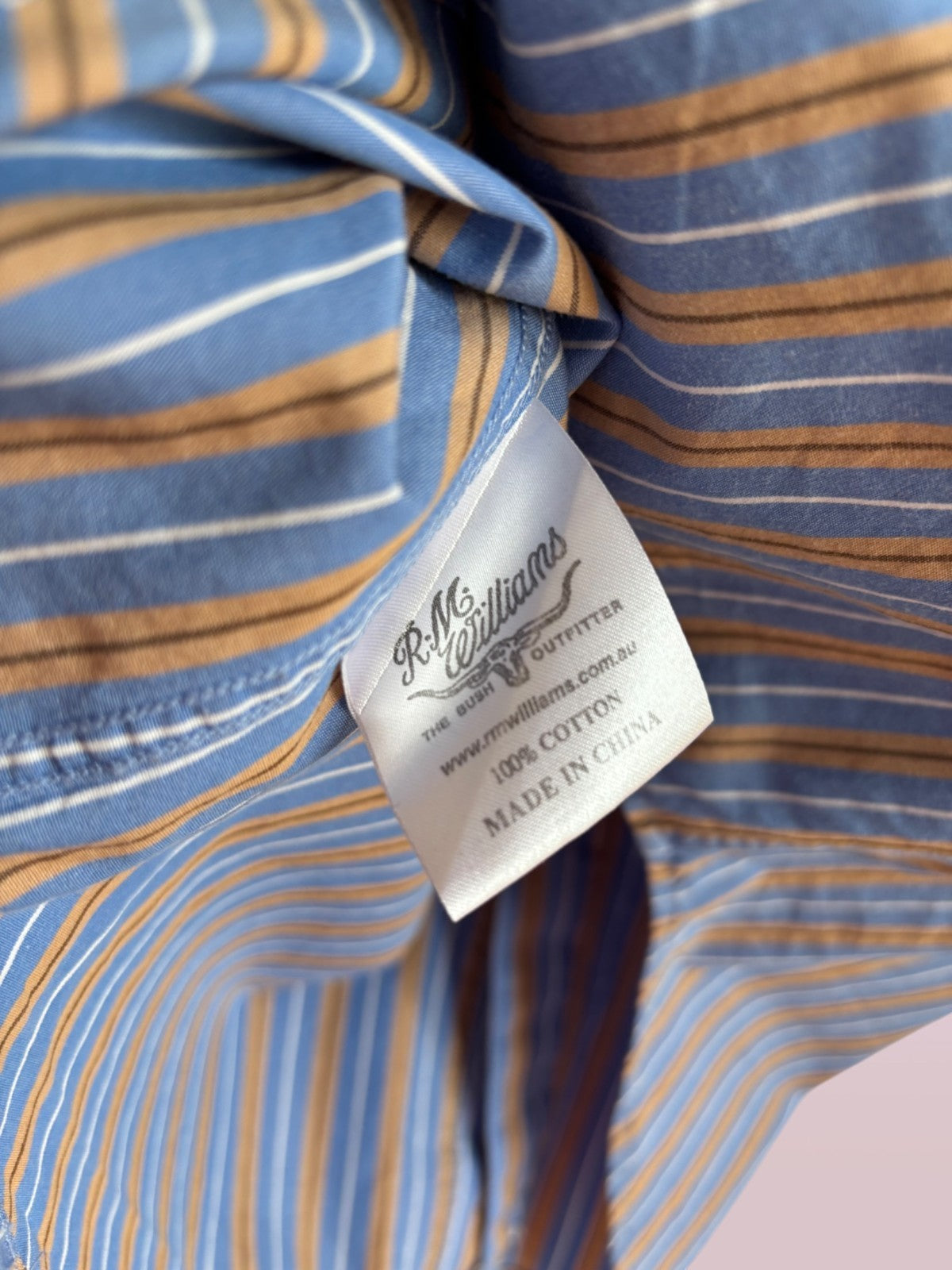 Close-up of a striped shirt with a label on a pink background