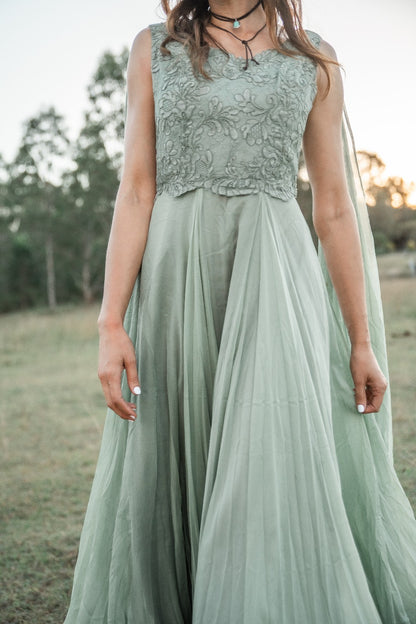 Person wearing a light green dress with lace top in an outdoor setting
