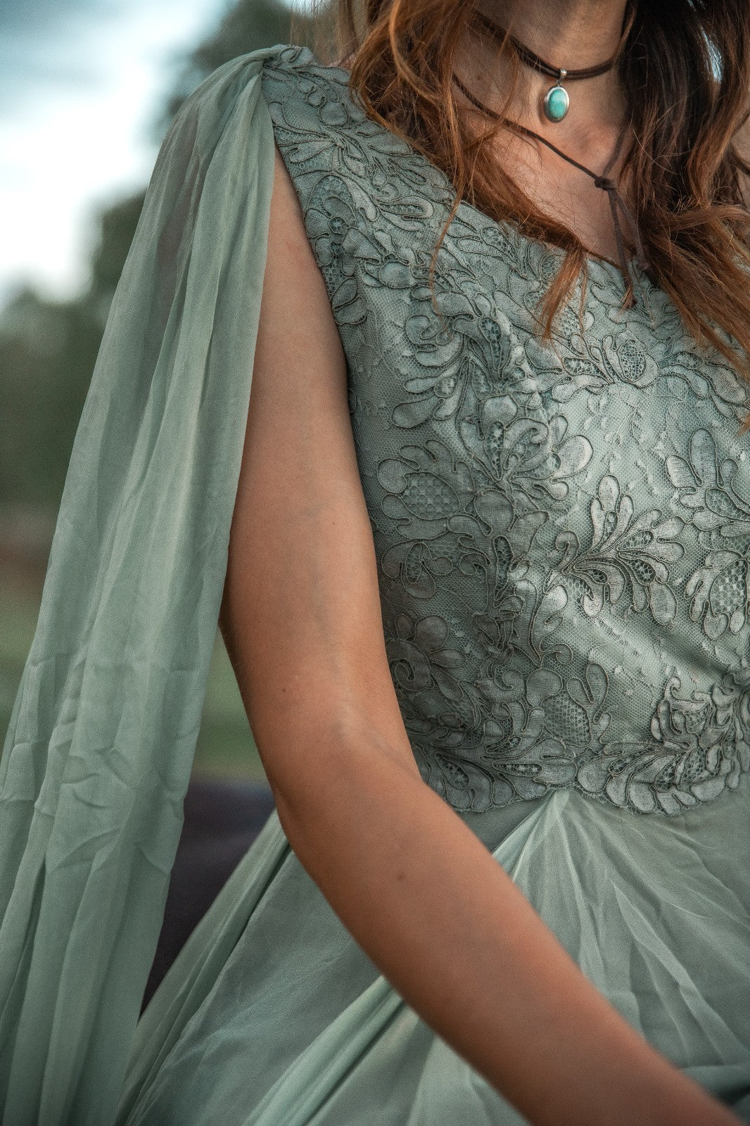 Person wearing a green embroidered dress with a blurred background