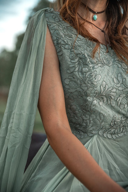 Person wearing a green embroidered dress with a blurred background