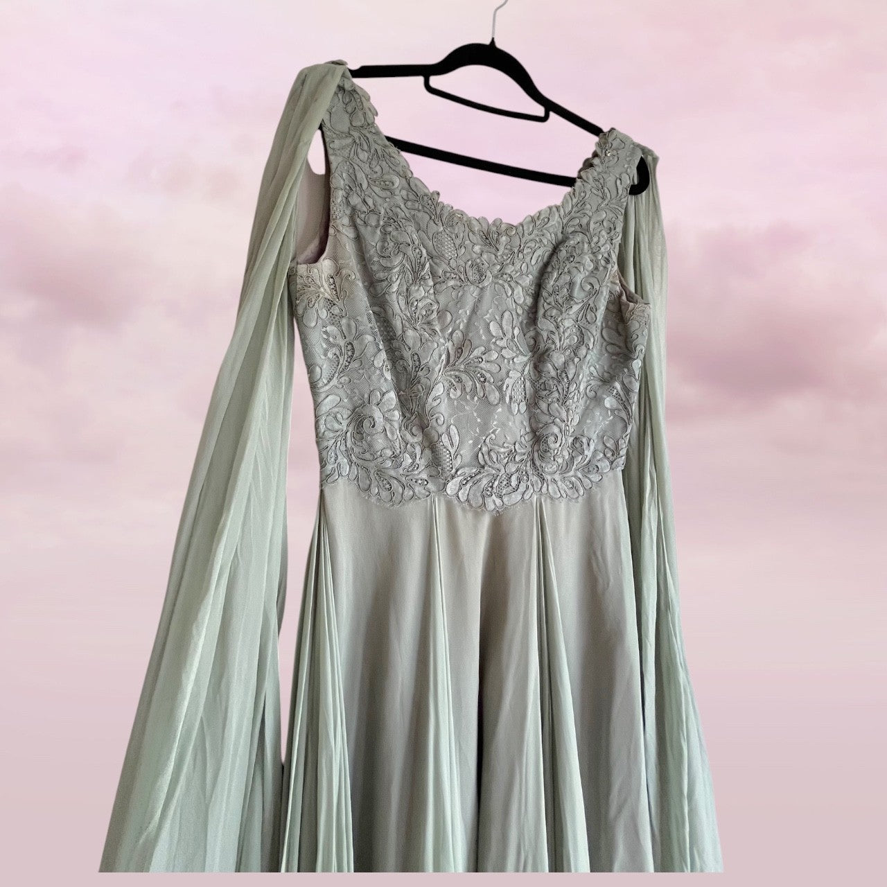 Mint green dress with lace detailing on a hanger against a pink background