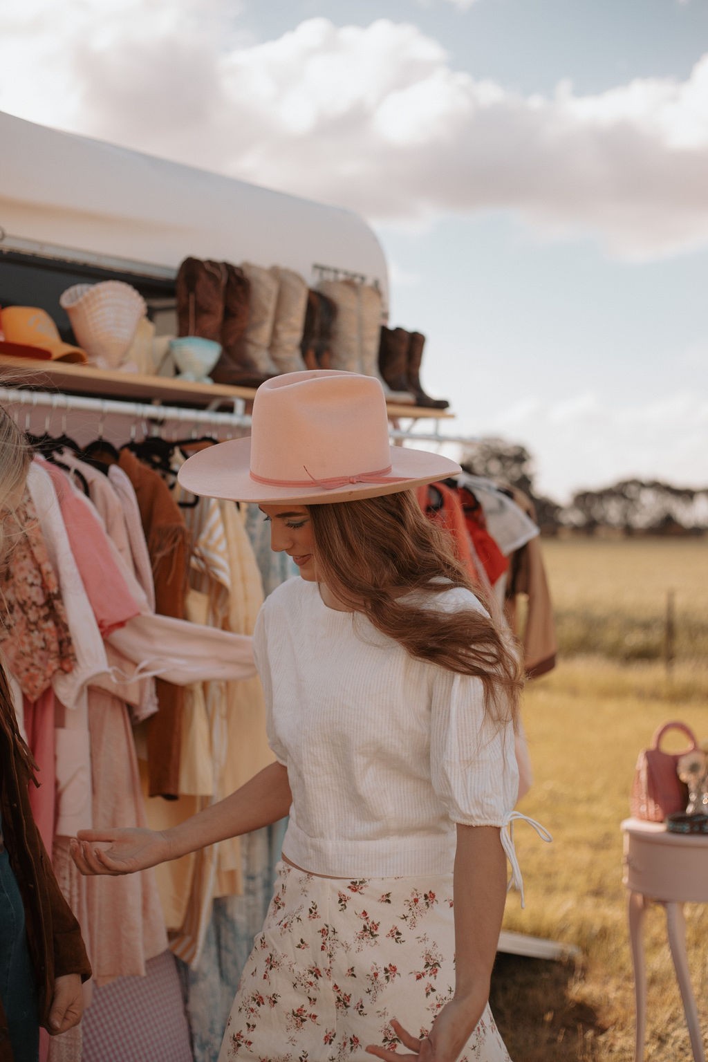Woman shopping at an outdoor market with a field and sky in the background