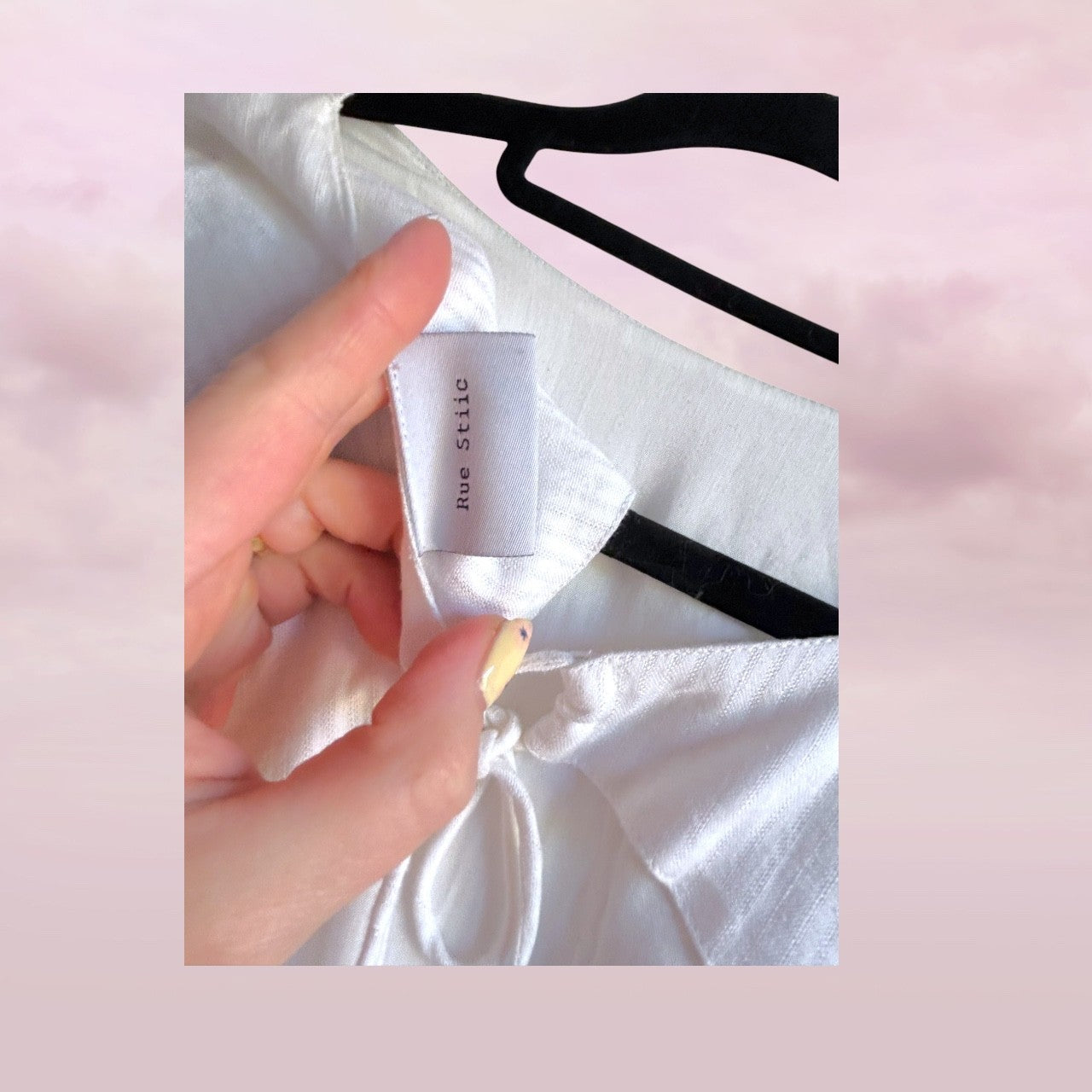 White shirt with a visible label held by a hand against a pink background