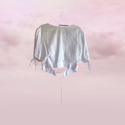 Light gray crop top on a hanger against a pink gradient background