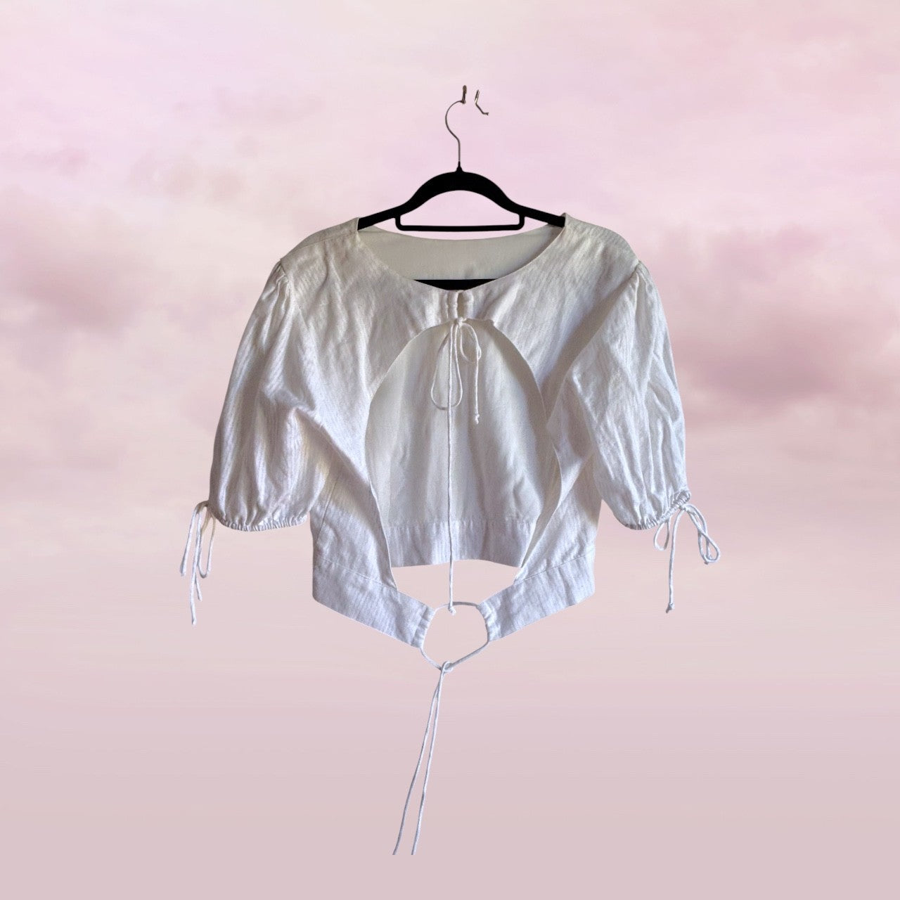 White crop top with cut-out design on a pink background