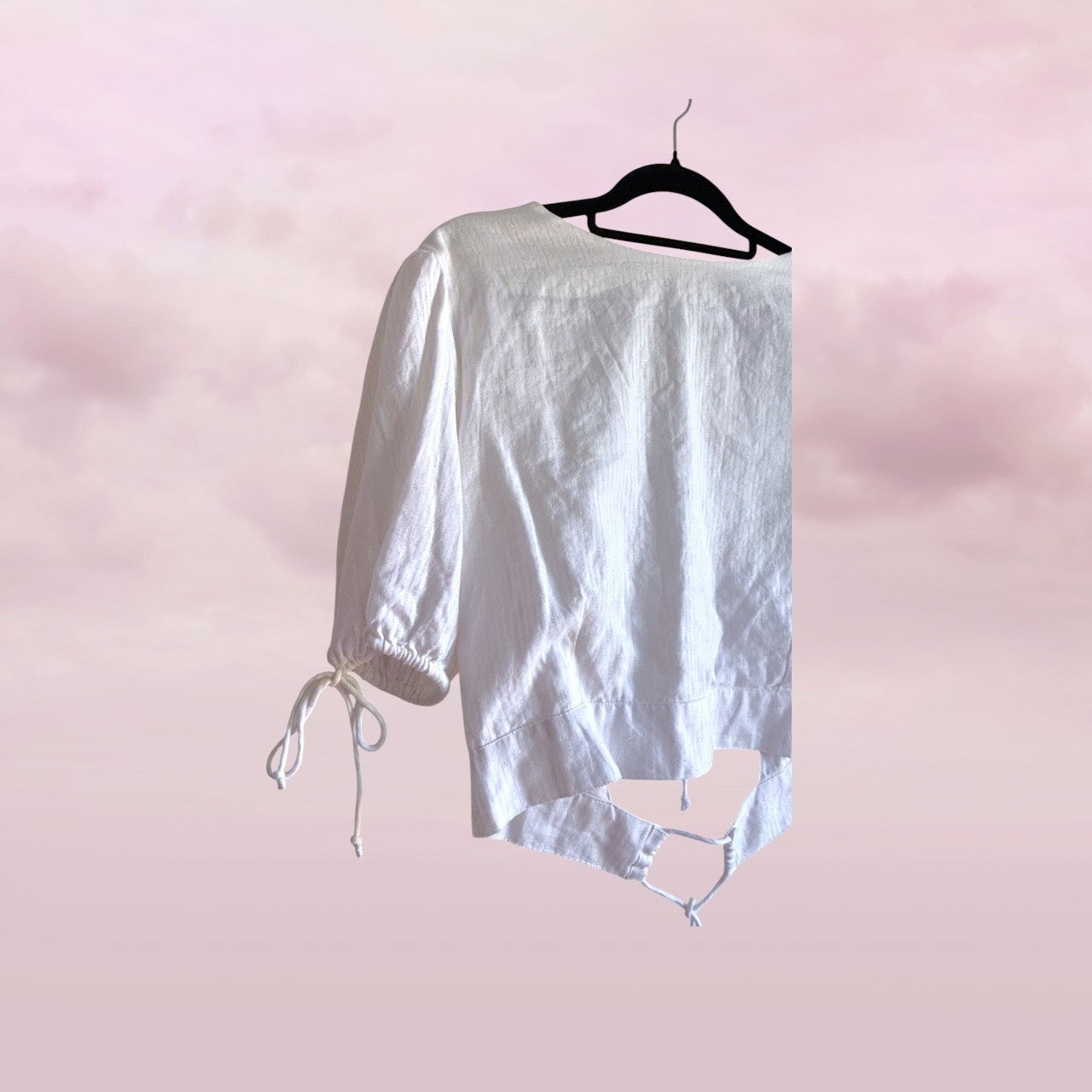 White linen shorts on a hanger against a pink gradient background