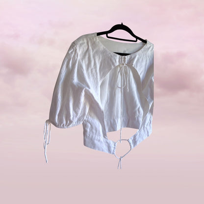 White blouse with short sleeves on a hanger against a pink background