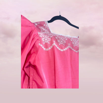 Pink nightgown with lace details on a hanger against a pink background