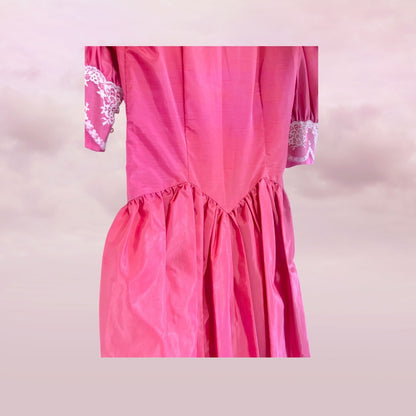 Pink dress with lace details on a light pink background