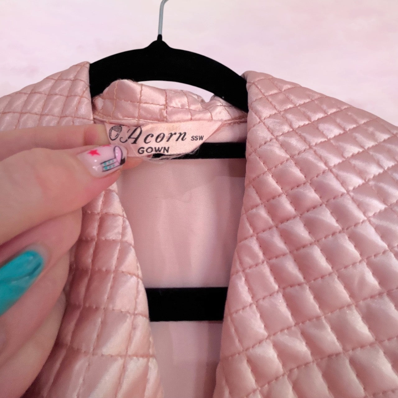 Pink quilted gown on a hanger with 'Acorn' label against a pink background