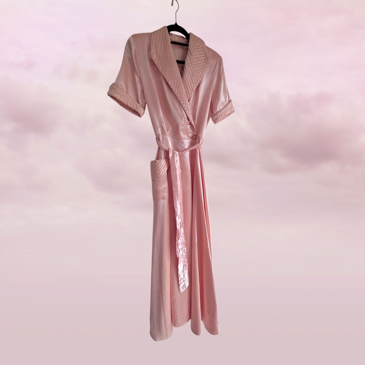 Pink satin robe on a hanger against a pink background
