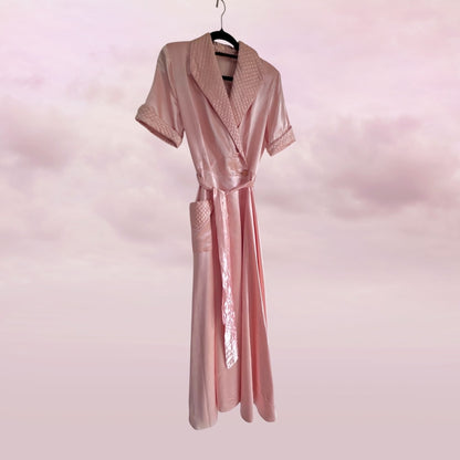 Pink satin robe on a hanger against a pink background