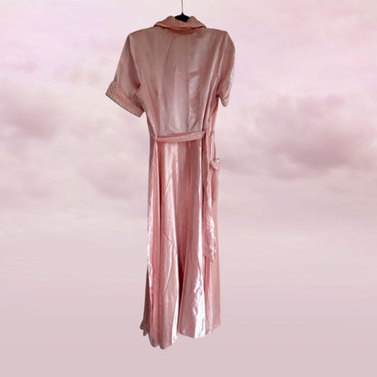 Pink satin robe on a hanger against a pink background