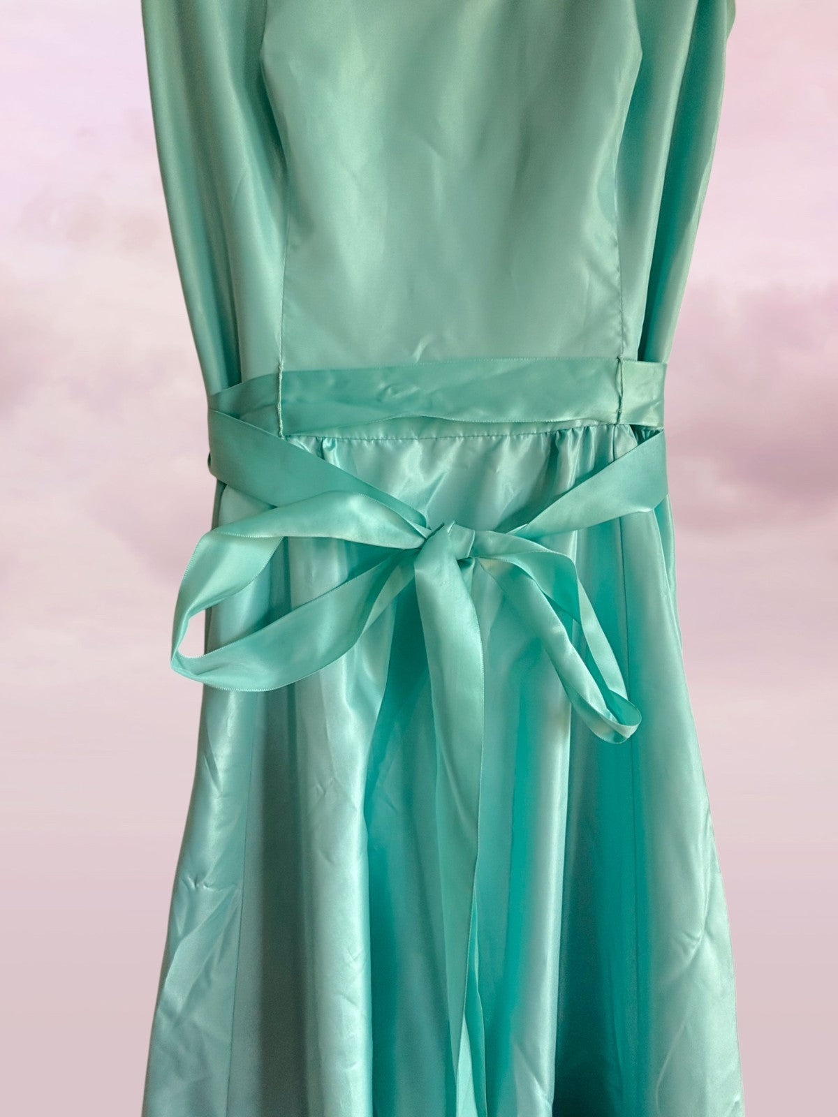 Teal dress with a bow on a pink background