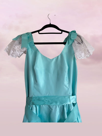 Teal dress with lace sleeves on a hanger against a light pink background