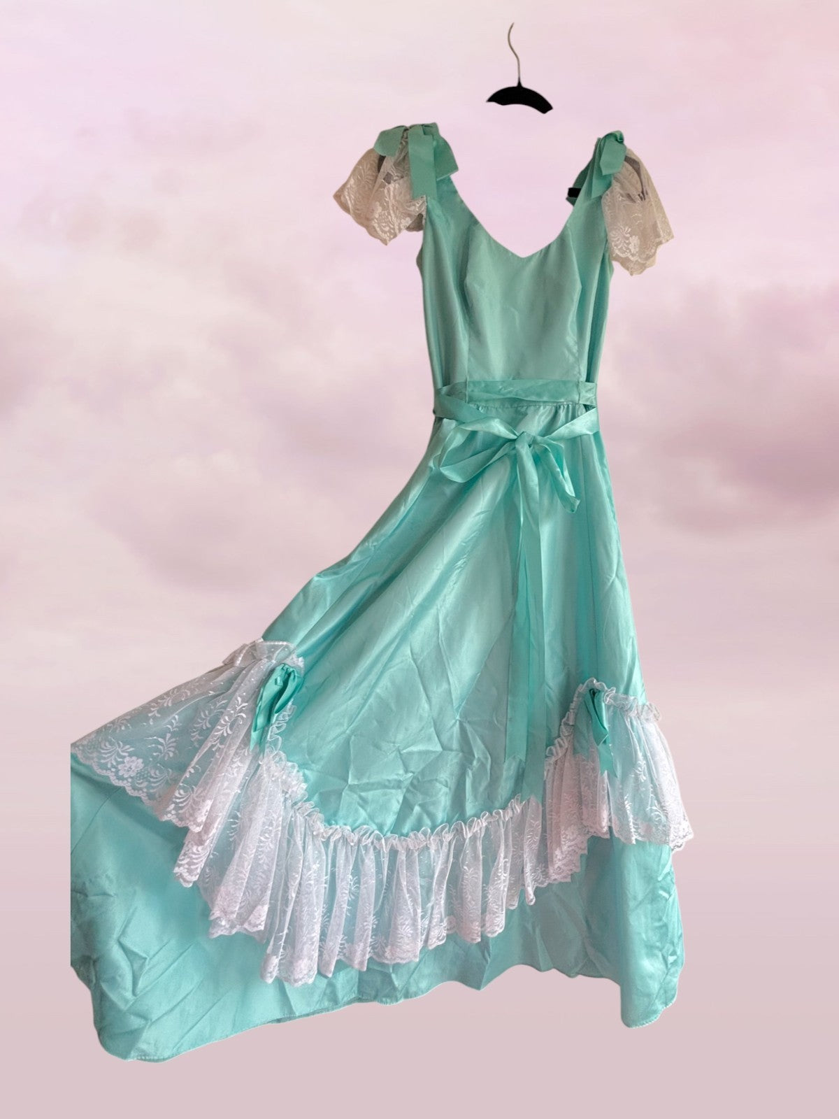 Teal vintage-style dress with lace details on a pink background