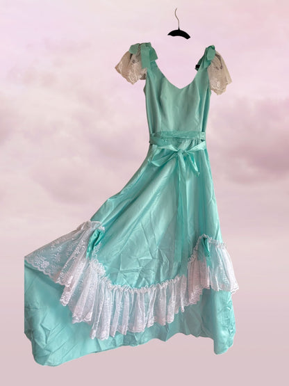 Teal vintage-style dress with lace details on a pink background