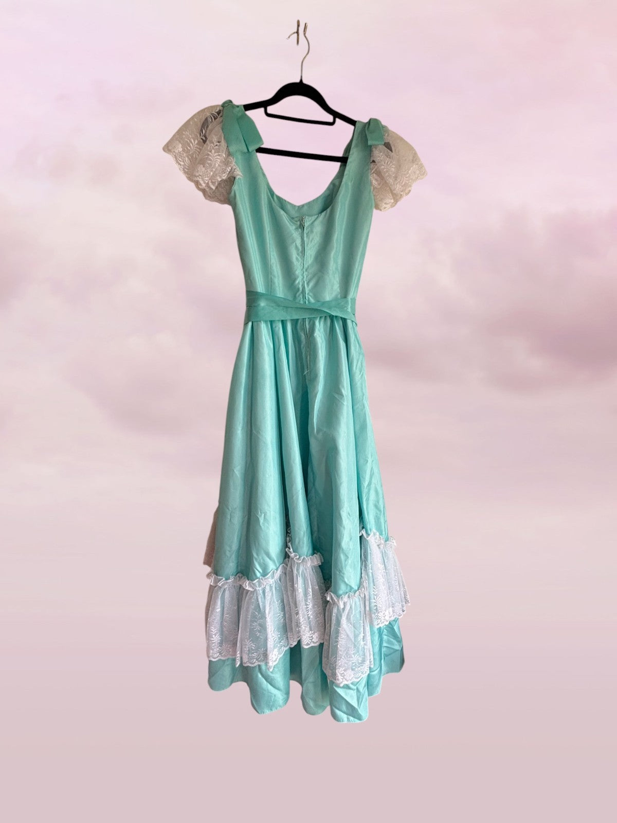 Teal dress with lace details on a pink background