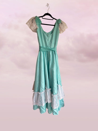 Teal dress with lace details on a pink background
