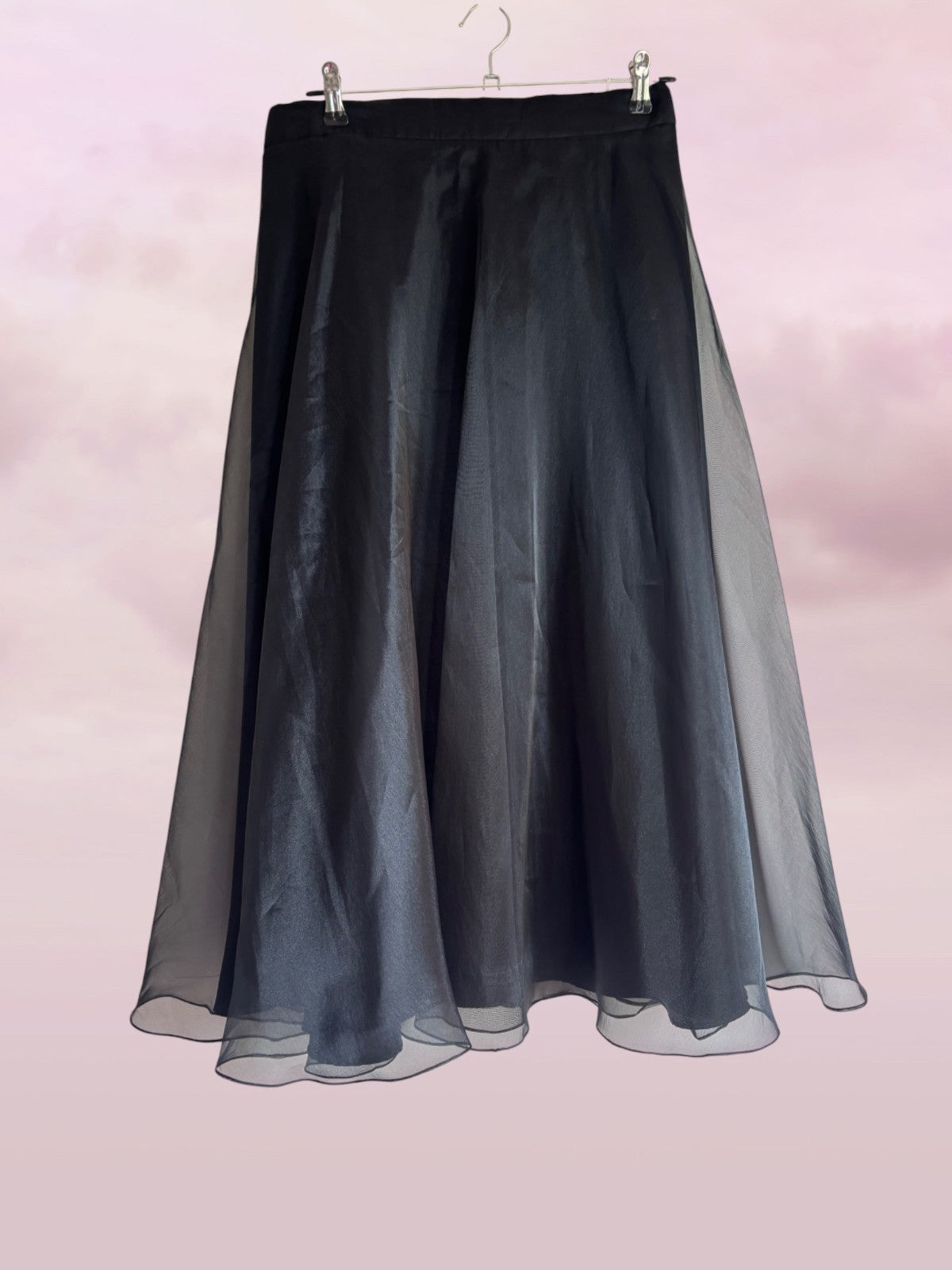 Black sheer skirt on a hanger against a pink background