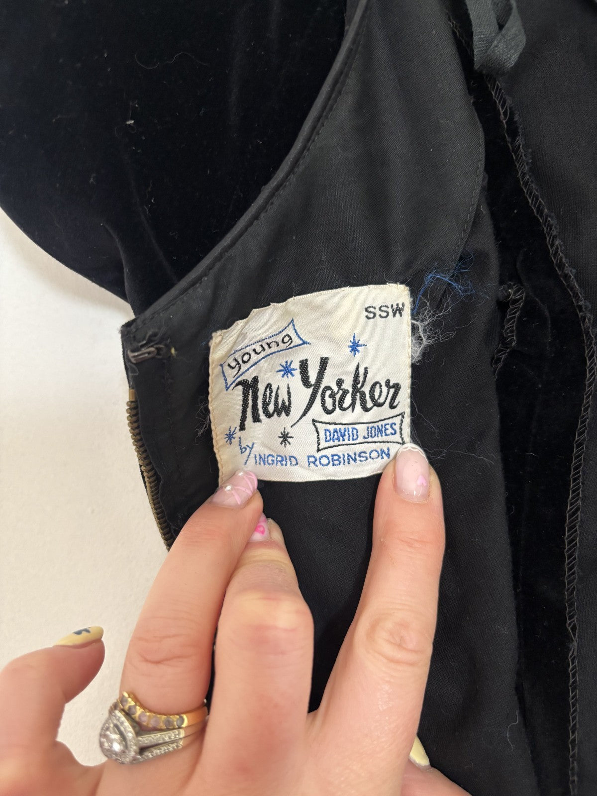 Close-up of a 'Young New Yorker' label on a black garment with a hand holding it.