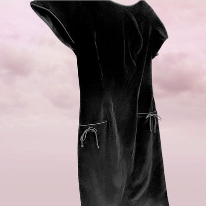 Black dress with sheer sleeves on a pink background