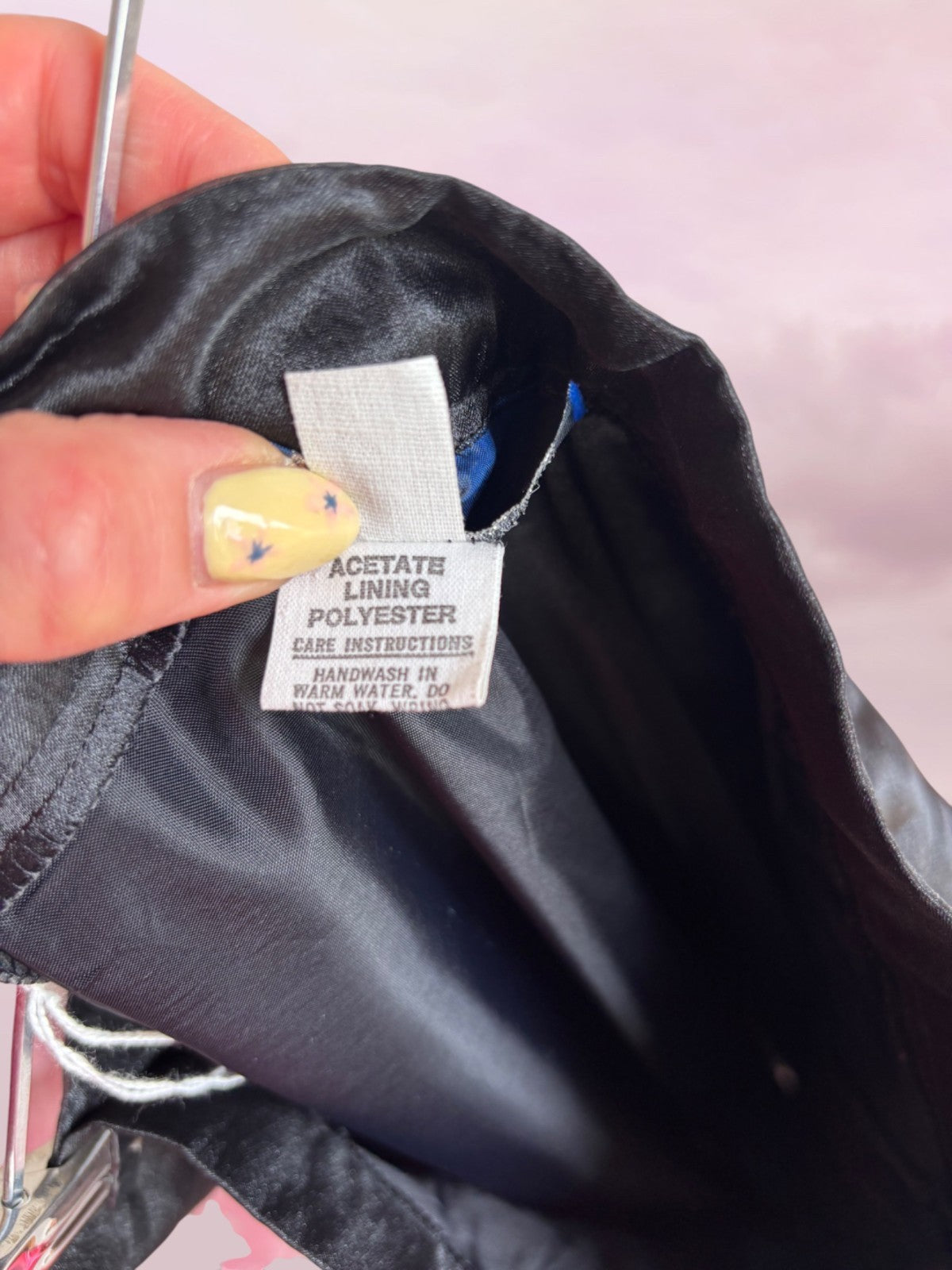 Close-up of a label on a black garment with a pink background