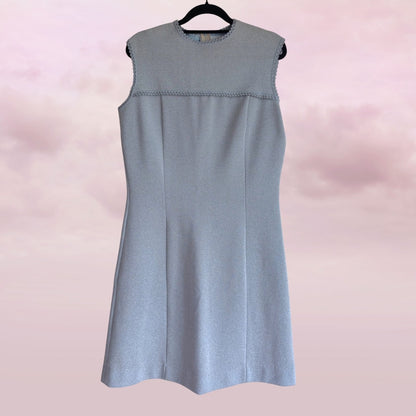Light blue sleeveless dress on a hanger against a pink background