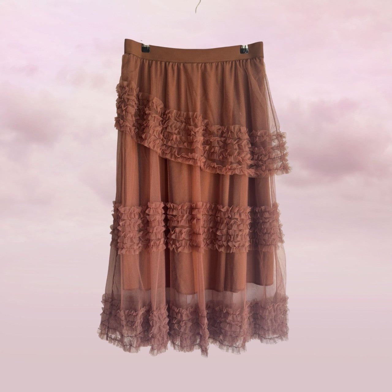 Brown ruffled skirt on a hanger against a pink background
