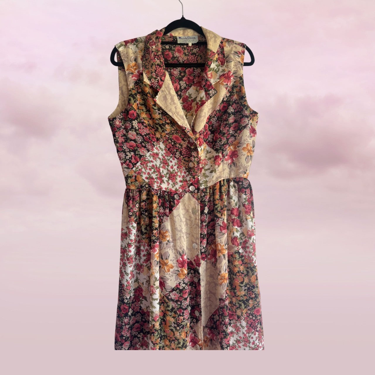 Floral patterned dress on a hanger against a pink background