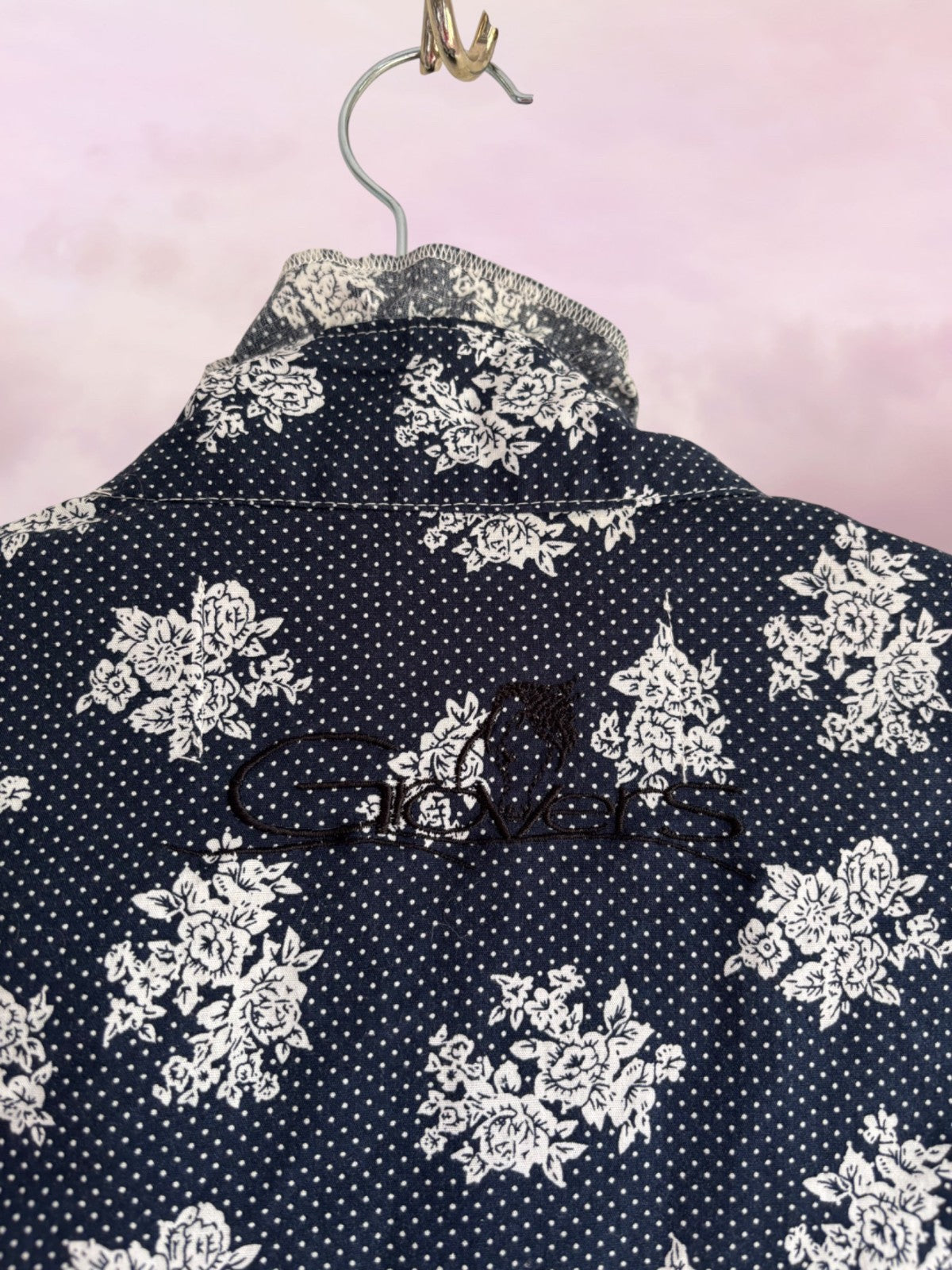 Navy blue shirt with white floral pattern on a pink background