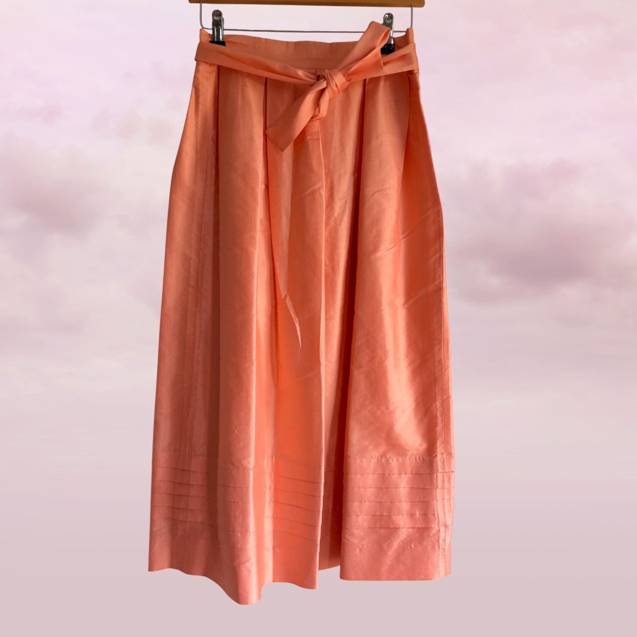 Peach-colored skirt with a tie waist on a pink background