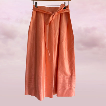 Peach-colored skirt with a tie waist on a pink background