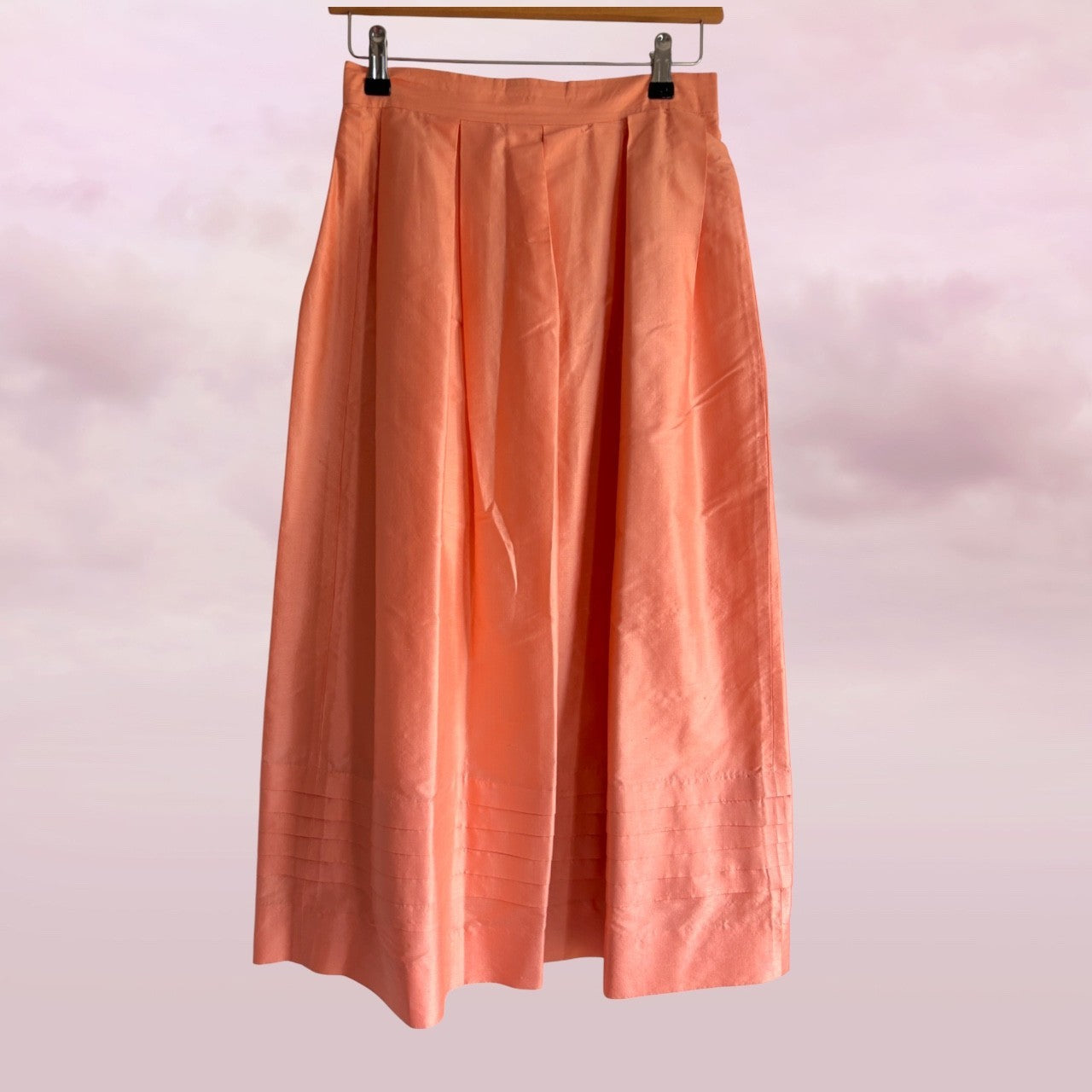 Peach-colored skirt hanging against a light pink background
