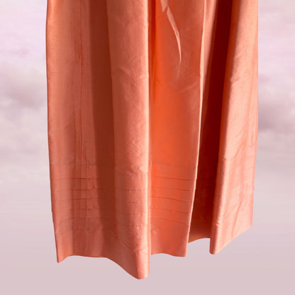 Coral-colored fabric with pleated texture on a light pink background