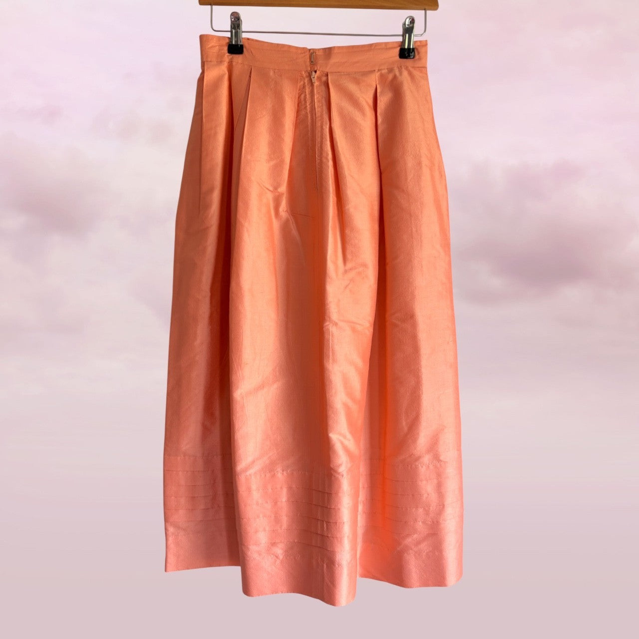 Peach-colored skirt hanging against a light pink background