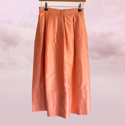 Peach-colored skirt hanging against a light pink background