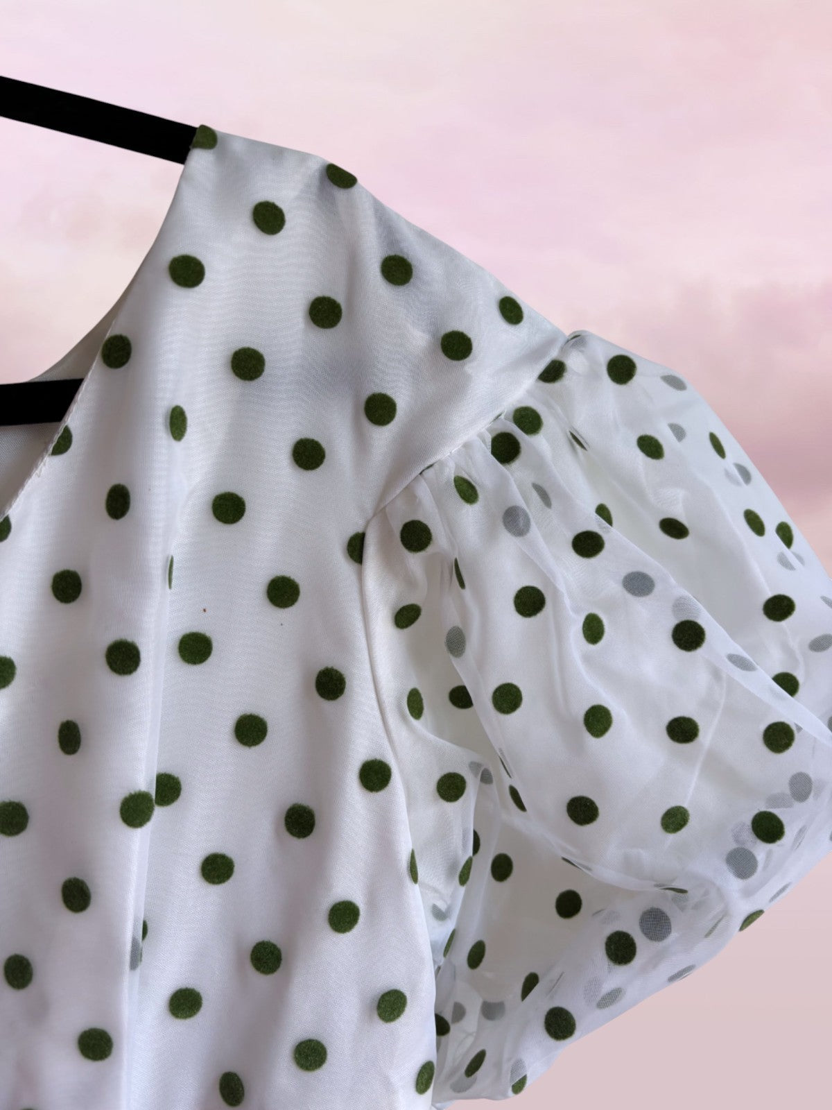 White blouse with green polka dots on a pink background