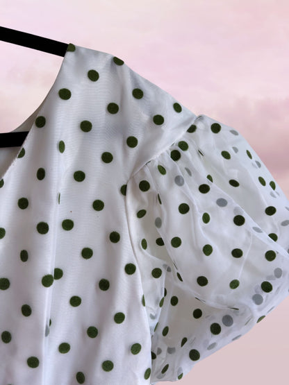 White blouse with green polka dots on a pink background