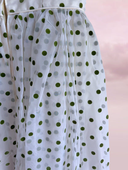 White dress with green polka dots on a pink background