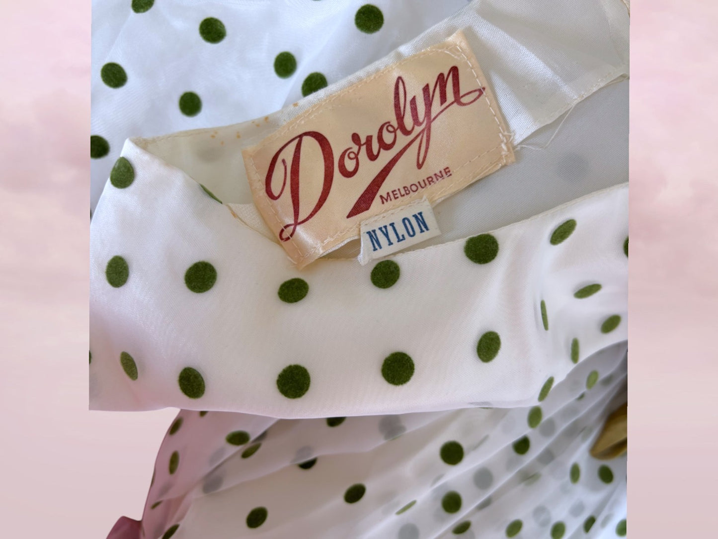Polka dot fabric with a 'Dorolyn' label on a pink background