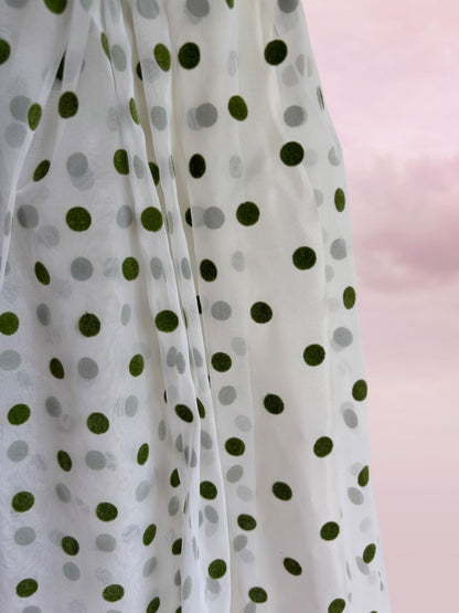 White fabric with green and gray polka dots on a pink background