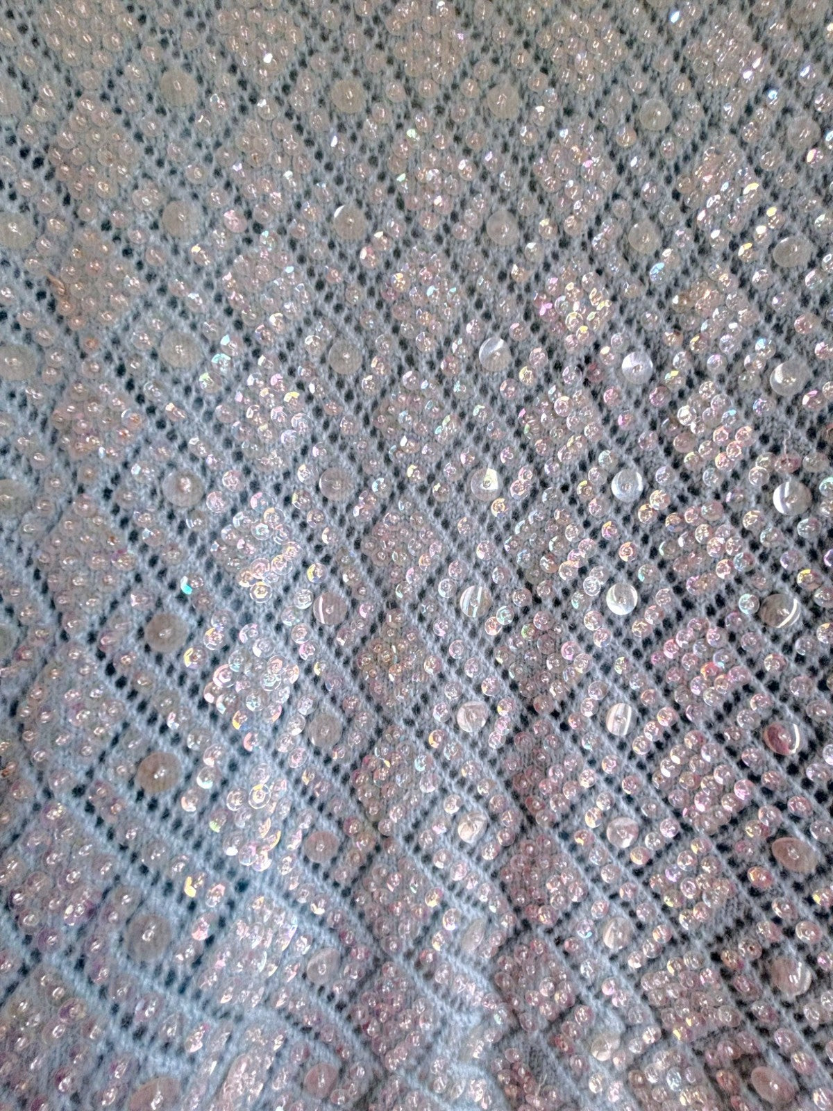 Close-up of a textured fabric with a diamond pattern and metallic sheen.