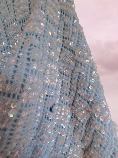 Close-up of a textured fabric with sequins on a light pink background