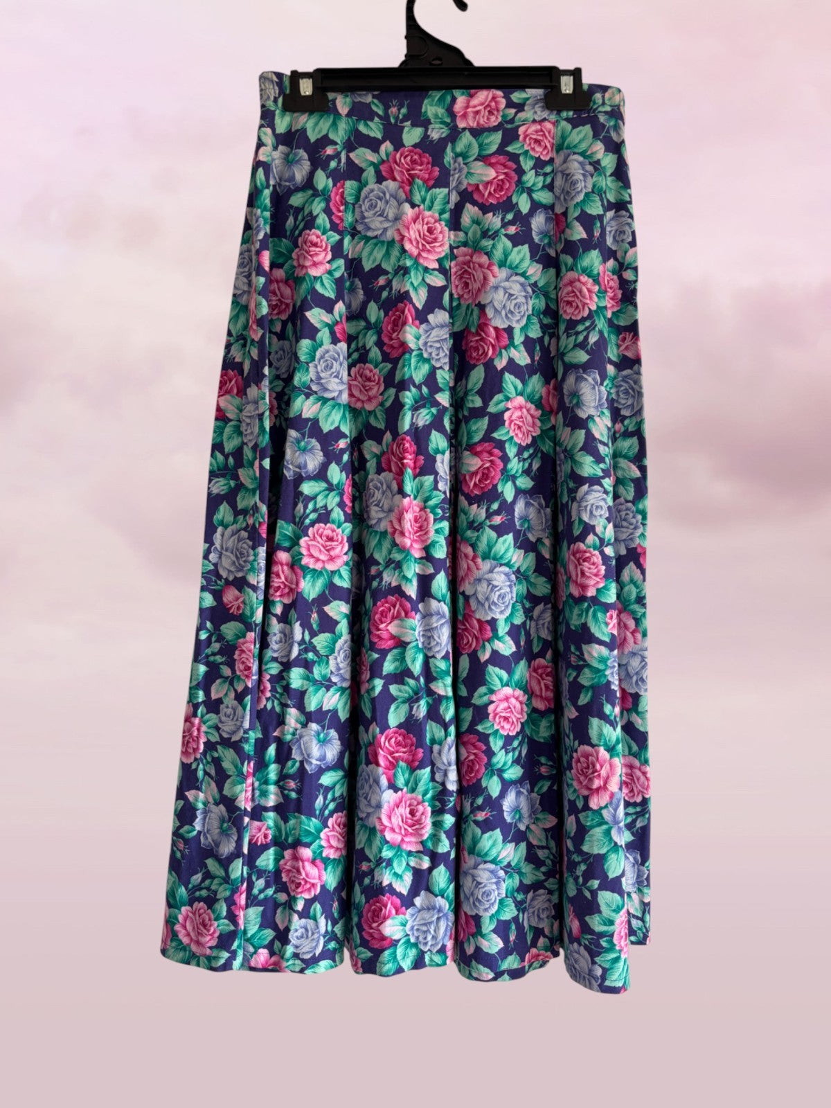 Floral patterned skirt on a hanger against a light pink background