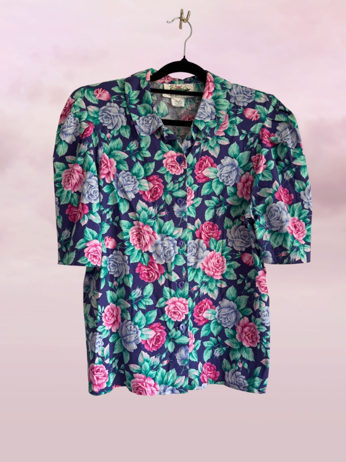 Floral patterned blouse on a hanger against a light pink background